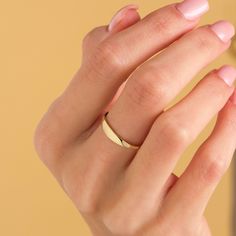 a woman's hand with a gold ring on her left wrist and pink manicured nails