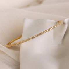 Our Classic Diamond Tennis Bangle is a dainty gold piece adorned with sparkling pavé stones, exuding elegance and sophistication. Perfect for any occasion, this versatile bracelet can be worn alone for a subtle touch of glamour or stacked with other bracelets for a classy, layered look ♡ SKU: RR-BR065 Product Details Material: 18K Gold Over Brass Finish: 18K Gold Featuring ~2.5mm wide Diamond Bangle Bracelet with CZ Pavé Diamond Stones Featured Styles Part of our Diamond & Pavé Collection Model Bracelet Tennis, The Bangles, Diamond Bangles Bracelet, Stone Feature, Gold Piece, Diamond Bangle, Layered Look, Tennis Bracelet, Diamond Stone