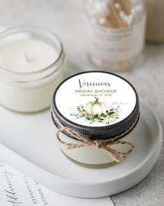 a candle and some jars on a white plate next to the label for an elegant bridal shower