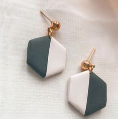 two tone earrings with green, white and gold accents on top of a white cloth