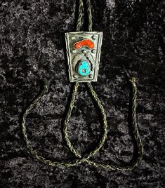 Vintage Viola Calavaza Sterling Silver Turquoise Bolo Tie in a Navajo Design. The sterling silver centerpiece measures approximately 3" x 2". Vintage from the 1960s, includes turquoise and coral. It is missing the metal tips that are usually on a bolo tie, but actual silver piece is in good condition. Silver Southwestern Turquoise Necklace For Western Events, Southwestern Silver Turquoise Necklace For Western Events, Southwestern Style Silver Turquoise Necklace For Western-themed Events, Silver Turquoise Necklace For Western-themed Events, Western Silver Turquoise Necklace With Concho, Artisan Silver Jewelry For Rodeo, Vintage Silver Turquoise Necklace With Patina, Handmade Western Silver Turquoise Necklace, Vintage Turquoise Necklace With Concho Detail