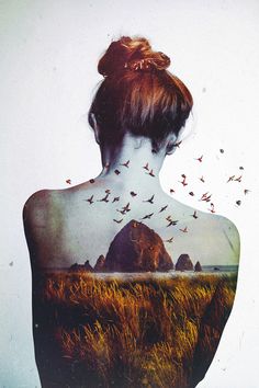 the back of a woman's body with birds flying over her head and mountains in the background