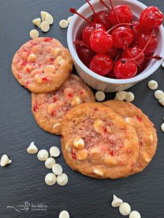 three cookies with cherries and marshmallows are on the table next to a bowl of cherries