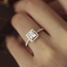 a woman's hand with a diamond ring on top of her finger and an engagement band