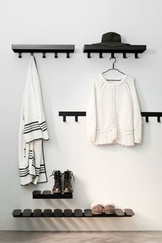 a pair of shoes sitting on top of a wooden shelf next to a coat rack