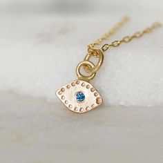 "Solid 14k Gold and teal blue Evil Eye modern minimalist charm necklace.  Handmade evil eye necklace set with a teal blue diamond center.  The charm hangs from a 1.3mm 14k yellow gold chain with  lobster clasp.  This dainty gold charm is the perfect size for everyday wear! Details: Eve dimensions - 8mm wide x 5mm tall (without bail) diamond - 1.7mm teal blue diamond (treated to enhance color) chain - 1.3mm cable chain with lobster clasp Length - Choose at checkout Made to order **Please note the photos are enlarged on your computer screen. Please refer to a ruler with the dimensions I have listed to ensure you are aware of the exact scale of the item before purchasing. Thank you! **Check out the rest of my necklace collection here: https://www.etsy.com/shop/LilianGinebra?ref=seller-platfor 14k Gold Evil Eye Jewelry Gift, Dainty 14k Gold Evil Eye Jewelry, Fine Jewelry With Blue May Birthstone, Fine Jewelry Blue May Birthstone, Blue Birthstone 14k Gold Jewelry, Blue Fine Jewelry For May Birthstone, Blue May Birthstone Fine Jewelry, Blue Round Pendant Jewelry For May Birthstone, Fine Jewelry 14k Gold Blue Birthstone Necklace