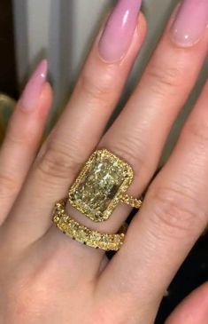 a close up of a person's hand with a ring on their finger and an engagement ring in the other hand