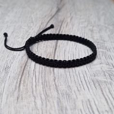 a black string bracelet on top of a wooden table