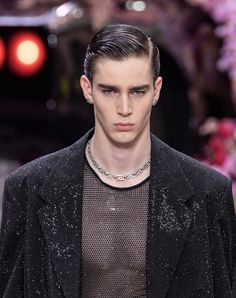 a male model wearing a black jacket and silver necklace on the runway at paris fashion week