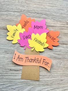 some paper flowers are sitting on top of a wooden table with the words i am grateful for