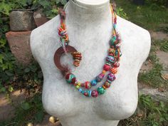 a necklace made with beads on a mannequin's head in a garden