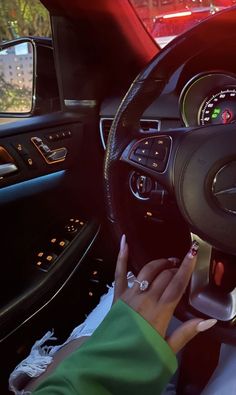 a woman driving a car with her hand on the steering wheel