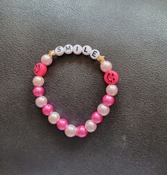 Pink Smile bracelet made with light and dark pink alternating round beads. Elastic band. Can be customized. Adjustable Round Pearl Bracelet With Colorful Beads, Pink Stretch Bracelet With Round Beads For Friendship, Adjustable Pink Bracelets With Letter Beads, Adjustable Pink Name Bracelet, Adjustable Round Pink Name Bracelet, Trendy Pink Hand-strung Stretch Bracelet, Pink Trendy Hand-strung Stretch Bracelet, Adjustable Pink Stretch Bracelet, Pink Stretch Bracelet With Colorful Beads For Friendship