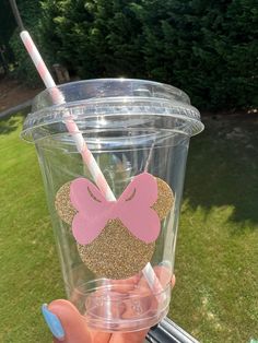 a person holding up a cup with a straw in it and a minnie mouse cutout on the lid