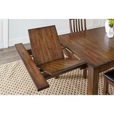 a wooden table with two chairs and a vase on top of it, in front of a rug