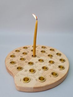 a candle that is sitting on top of a wooden coaster with holes in it and writing on the side