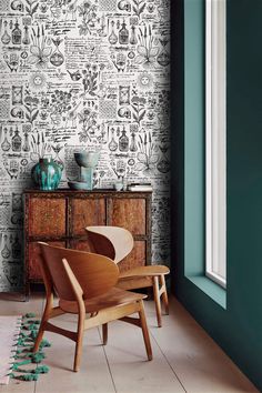 a chair sitting in front of a window next to a wall with many designs on it