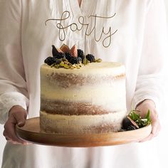 a person holding a cake with the word fetched on it and fruit on top