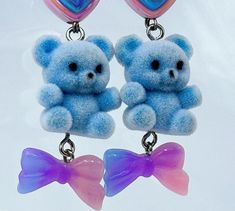 Add a touch of pastel goth cuteness to your outfit with these unique Blue Fuzzy Teddy Bear Kawaii Dangle Earrings! Featuring adorable heart beads and a sweet bow charm, these earrings are perfect for anyone who loves all things kawaii and cute. Stand out from the crowd with these one-of-a-kind accessories that are bound to make you smile every time you wear them. These handmade dangle earrings feature Cute AF fuzzy blue teddy bears adorned with pastel hearts and bows as sweet as candy. Get your thrillz on and add these one-of-kind earrings to your club wear collection. At Acid Thrillz, we value individuality and creativity by handmaking all items with care and saying F**k you to fast fashion by prioritizing quality and never creating duplicate items. Handmade Blue Kawaii Jewelry, Blue Kawaii Earrings For Gift, Cute Blue Earrings For Valentine's Day, Cute Handmade Light Blue Earrings, Cute Light Blue Earrings Gift, Cute Light Blue Earrings For Gift, Teddy Bear Kawaii, Bear Kawaii, Blue Teddy Bear