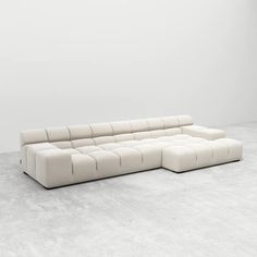 a large white couch sitting on top of a cement floor in front of a wall