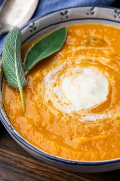 a bowl filled with carrot soup on top of a wooden table