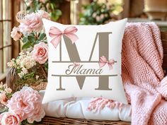 a white pillow with pink bows and the letter m on it sitting in a wicker chair