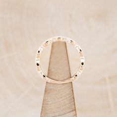 a gold wedding ring sitting on top of a piece of wood