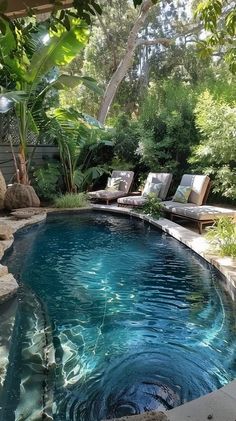 a swimming pool surrounded by lush green trees and rocks, with chaise lounges on the side