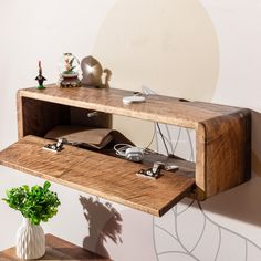 a wooden shelf with electronic equipment on it and a potted plant next to it