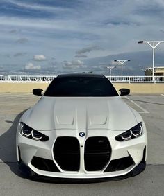 the front end of a white car parked in a parking lot