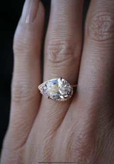 a woman's hand with an oval shaped diamond ring on top of her finger