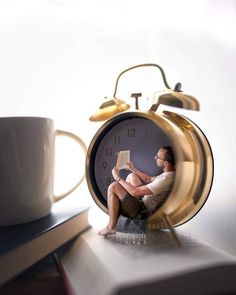 an alarm clock sitting on top of a book next to a cup