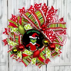 the grino christmas wreath is hanging on a white door with green and red decorations