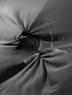 black and white photo of an unmade bed with the sheets pulled back to reveal fabric