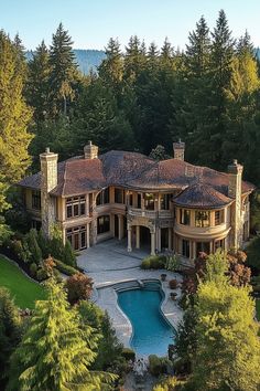 an aerial view of a house with a pool in the foreground and trees surrounding it