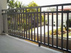 an empty balcony with black iron railings and trees in the background