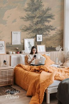 a woman is sitting on her bed with a laptop and looking at the screen she is reading