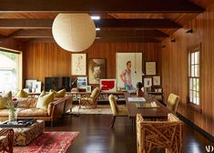 a living room filled with lots of furniture and wooden paneled walls next to windows