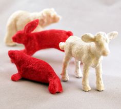 three small toy animals are shown on a table top, one is white and the other is red