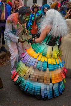 a man in a colorful dress with lots of paint on his face and hands, standing next to a woman