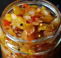 a glass jar filled with pickled vegetables on top of a table