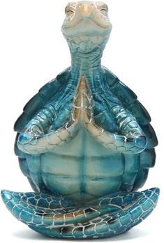 a blue glass turtle statue sitting on top of a white surface with its eyes closed