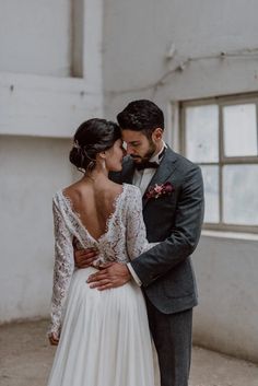 a bride and groom standing close to each other in front of an old building with windows