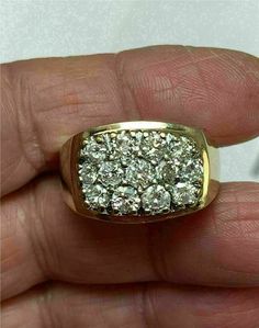 a man's hand holding a gold ring with white diamonds on it, in front of a white background