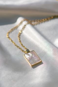 Add a touch of elegance with our Mother-of-Pearl Rectangular Minimalist Pendant Necklace. This stunning piece features a dainty rectangular mother-of-pearl pendant on a delicate gold chain, reflecting light beautifully for a sophisticated look. Perfect for those who love minimalist jewelry with a hint of luxury.

Features:

- Mother-of-Pearl Pendant: Rectangular and reflective, offering timeless elegance.

- Dainty Gold Chain: Lightweight and stylish, perfect for layering or wearing alone.
- Minimalist Design: Ideal for those who appreciate simple yet luxurious accessories.

Whether as a thoughtful gift or a personal treat, this necklace captures the beauty of minimalist design with a luxurious twist. Pearl And Gold Necklace, Mirror Necklace, Luxurious Accessories, Dainty Gold Chain, Delicate Gold Chain, Minimalist Pendant, Reflecting Light, Jewelry Mirror, Pearl Necklaces