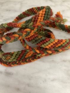 three pieces of multicolored knitted rope on white marble counter top with orange, green and yellow colors