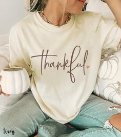 Celebrate the essence of gratitude with our Thankful Fall Comfort Colors Shirt, featuring the word "thankful" in a lovely cursive font with a delicate heart accent. Perfect for Thanksgiving and the fall season, this Thanksgiving shirt embodies warmth and appreciation. As one of our premium thankful tees, it offers unparalleled comfort and style. Ideal for any autumn gathering, this Thanksgiving t-shirt is a must-have addition to your wardrobe of autumn tees. Whether you're a thankful mama or sim Thanksgiving Vinyl Shirt Ideas, Thanksgiving Shirt Ideas For Women, Thankful Shirt Ideas, Thanksgiving Tees For Women, White T-shirt For Fall Gift, White T-shirt As A Fall Gift, White T-shirt For Fall Season Gift, Casual Letter Print Tops For Thanksgiving, Casual Tops With Letter Print For Thanksgiving