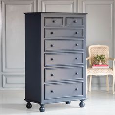 a grey chest of drawers sitting next to a chair