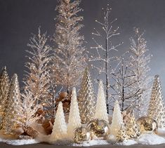 a group of christmas trees with snow on them and gold ornaments in front of it