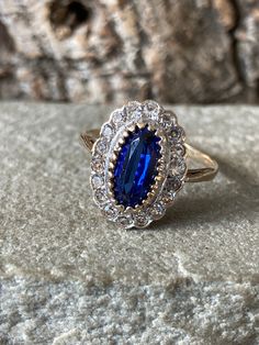 A Stunning vintage ring, a gorgeous oval faux Sapphire 10mm x 6mm surrounded by 18 sparkling faux Diamonds , pretty pierced setting in 9ct gold with a 9ct gold band , hallmarked in Birmingham 1991, Size O or US 7 , a lovely ring ! Vintage Cluster Ring With Halo Design, Victorian Style Gold Oval Cluster Ring, Victorian Oval Cluster Ring In Gold, Antique Gold Oval Cluster Ring, Victorian Oval Gold Cluster Ring, Victorian 14k Gold Oval Cluster Ring, Antique Oval Cluster Ring As Gift, Victorian Oval Cluster Ring In 14k Gold, Victorian Cluster Ring In 14k Gold, Oval Shaped